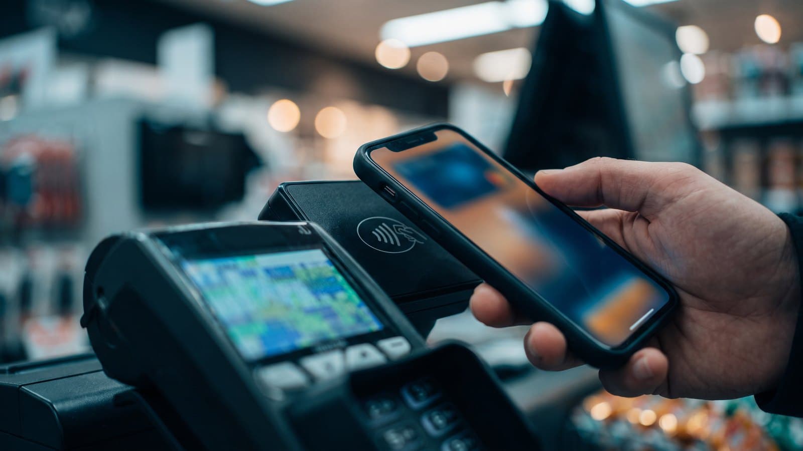 A smartphone showing a generic digital-wallet payment screen at a checkout, with a card reader, representing PayPal's digital-payments business and the collapsed takeover.
